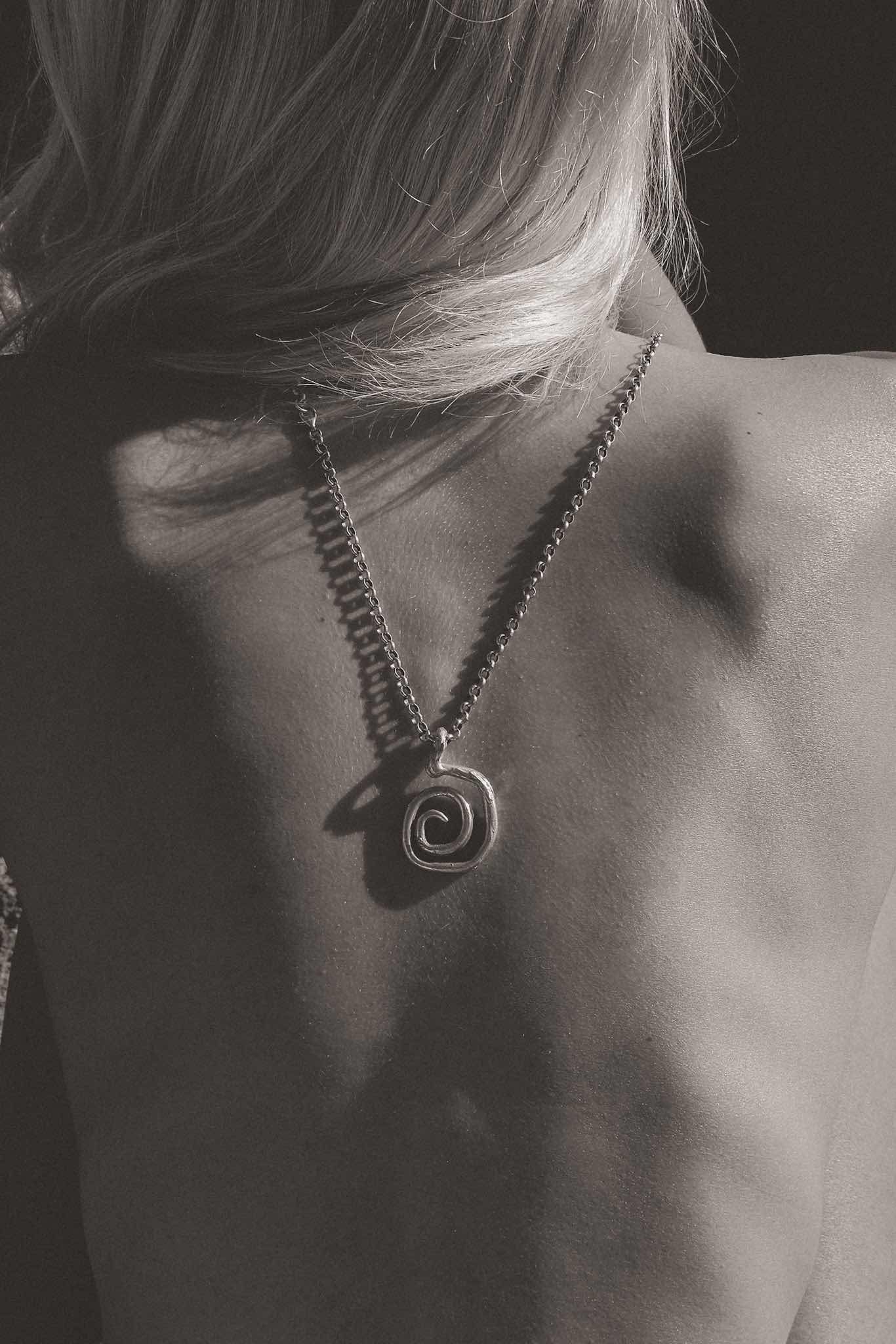 Black and white image of model with necklace draped on her back taken for a fashion brand in Ibiza