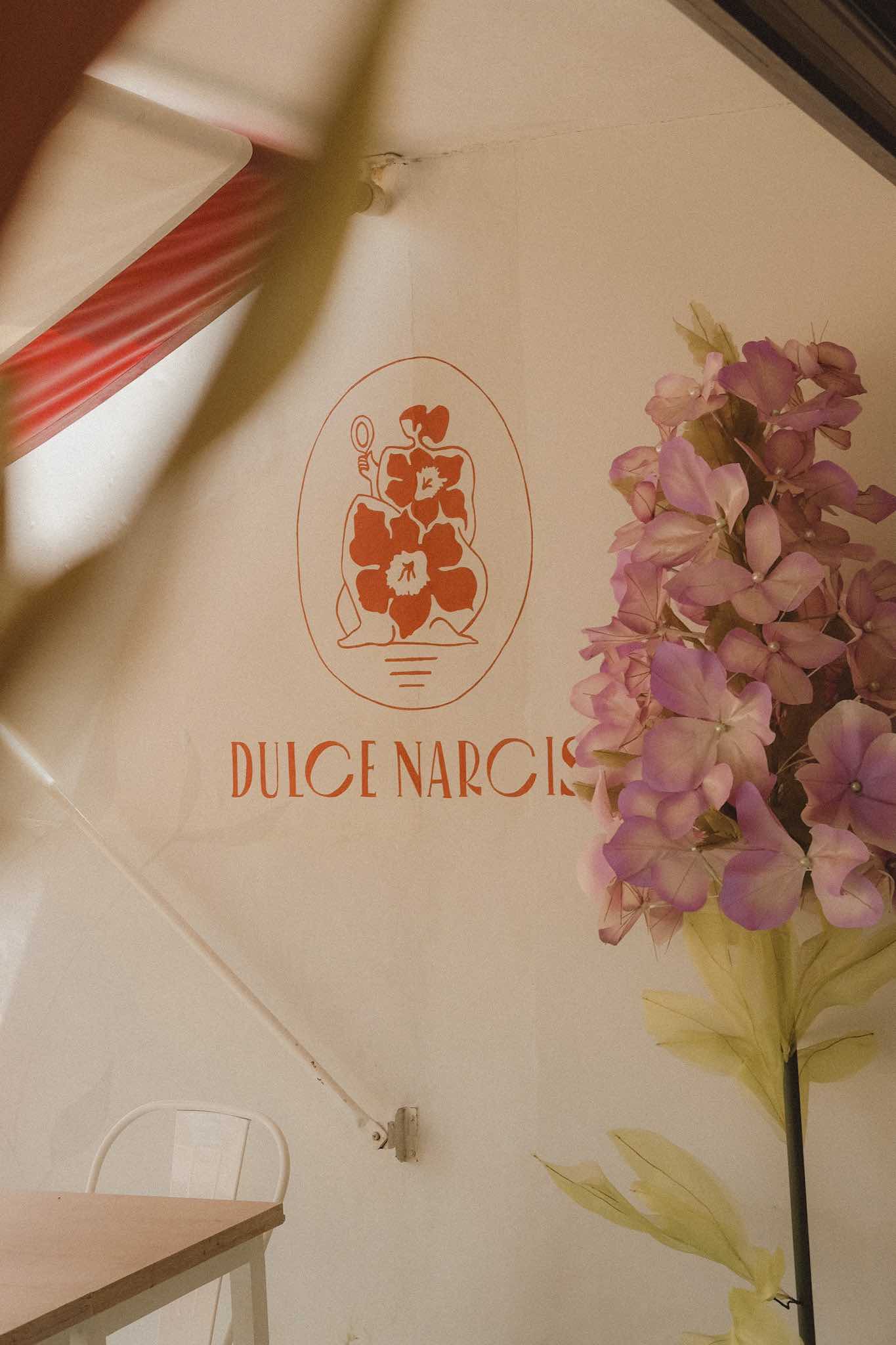 Close up interior photography of ice cream shop logo for Valladolid, Mexico ice cream shop. pink flower decorations on the right, red text graphics and cream wall colour.